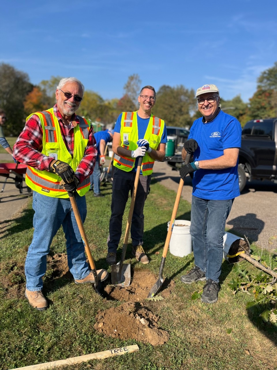 Ford employees smiling while digging a hole