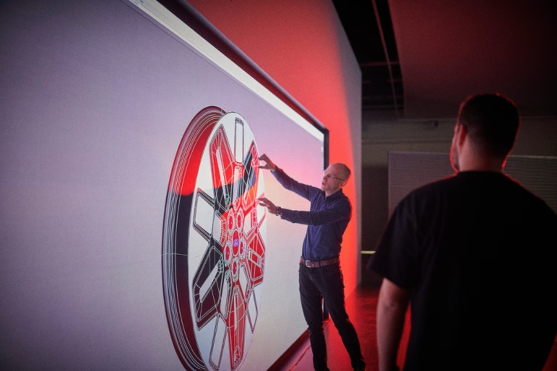 man pointing to large image of wheel
