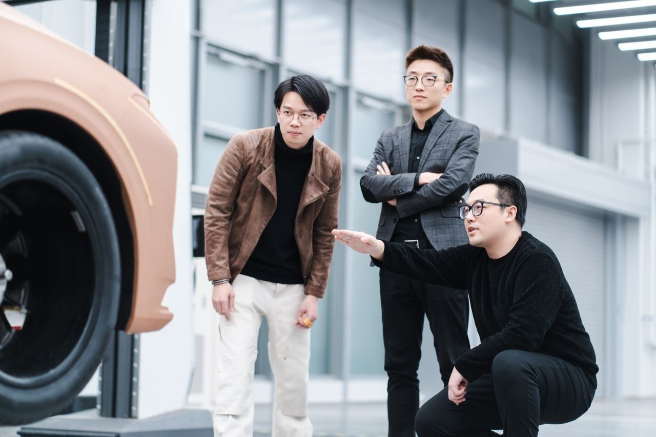 three designers discussing a clay model vehicle