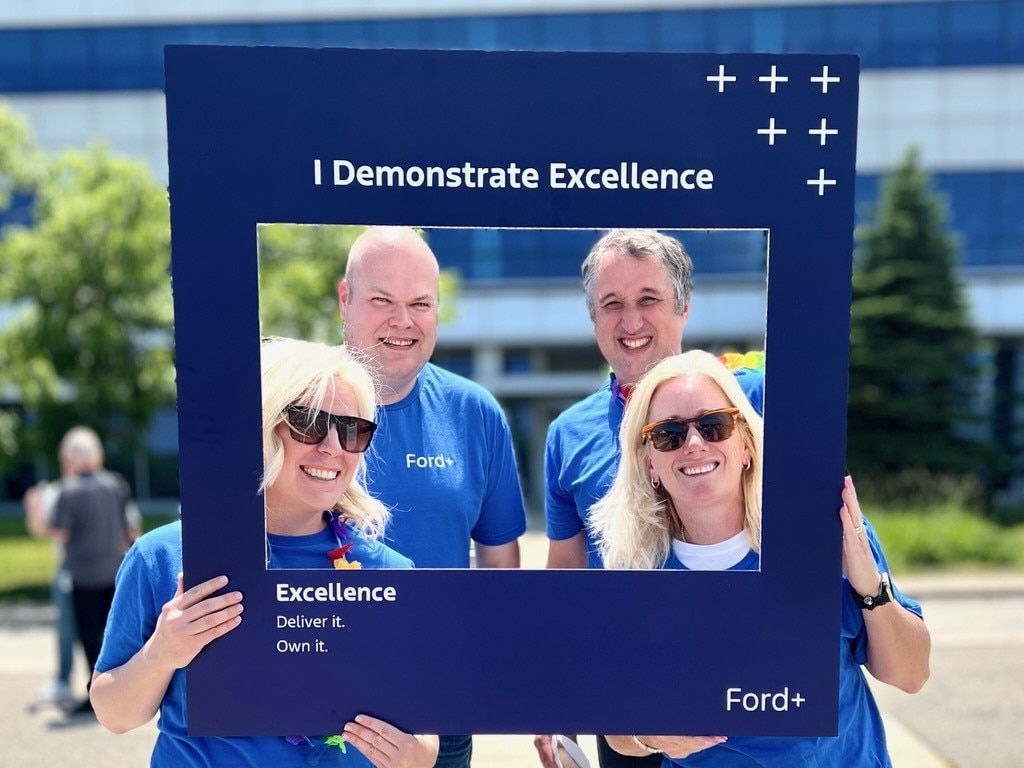 Four Ford employees taking a picture with a selfie frame 