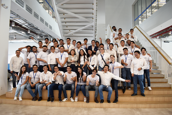 A group of individuals wearing white shirts smiling and posing together for a photo.