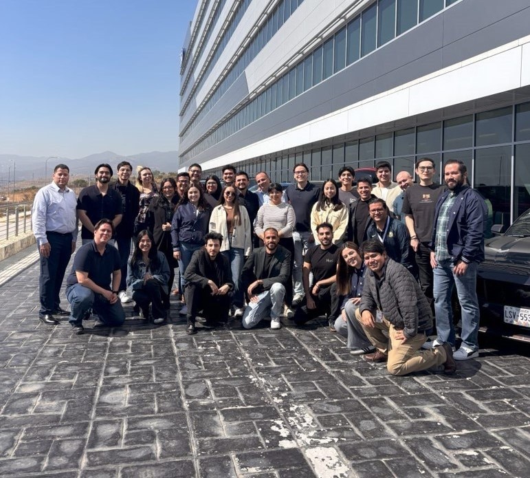 A cheerful group of people stands together for a photo in front of a modern building.