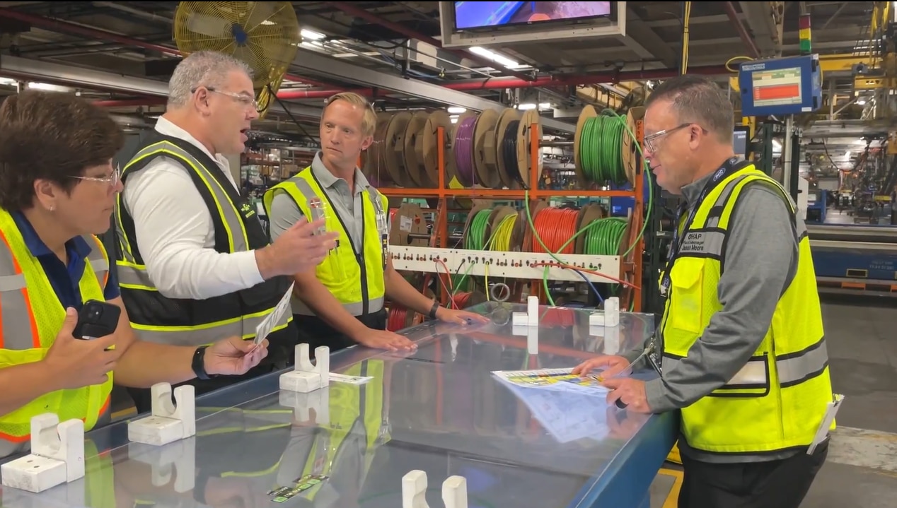 Employees in high visibility vests listening to Bryce Currie