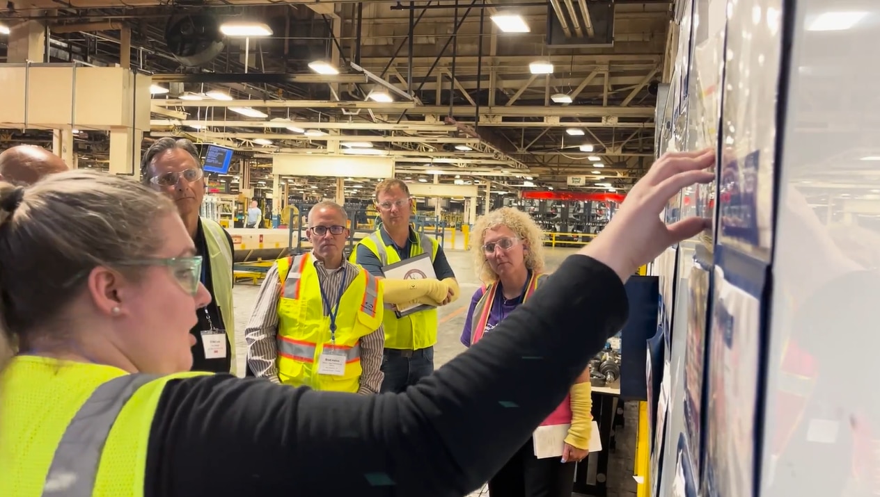 Employees in high visibility vests listening to production supervisor