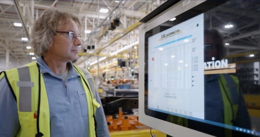 Employee in high visibility vest looking at screen of data