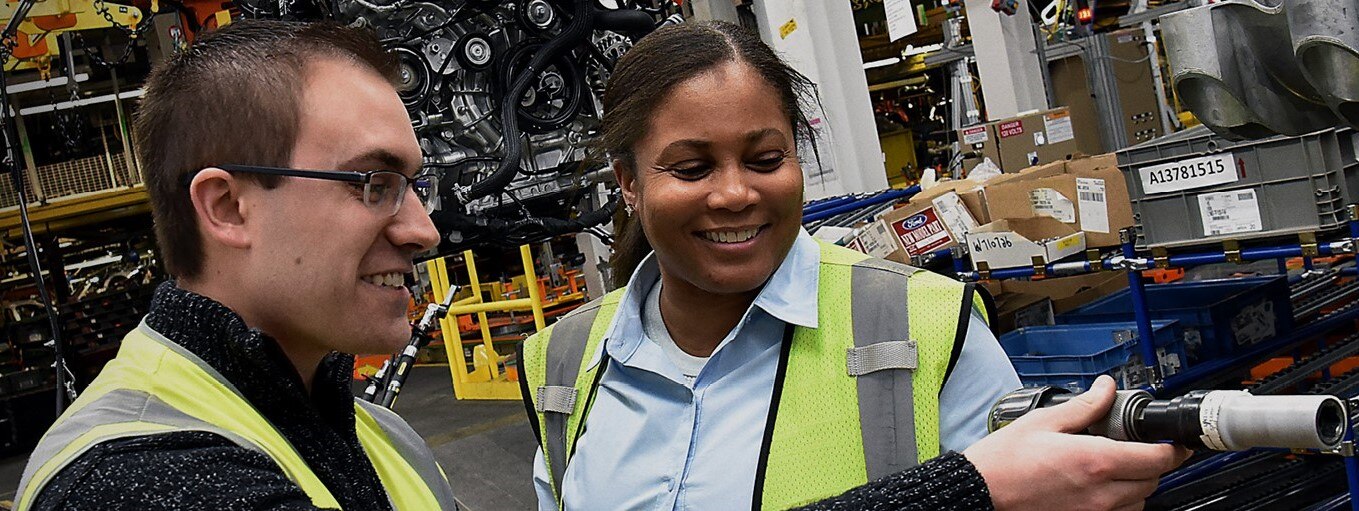 two employees examining a part