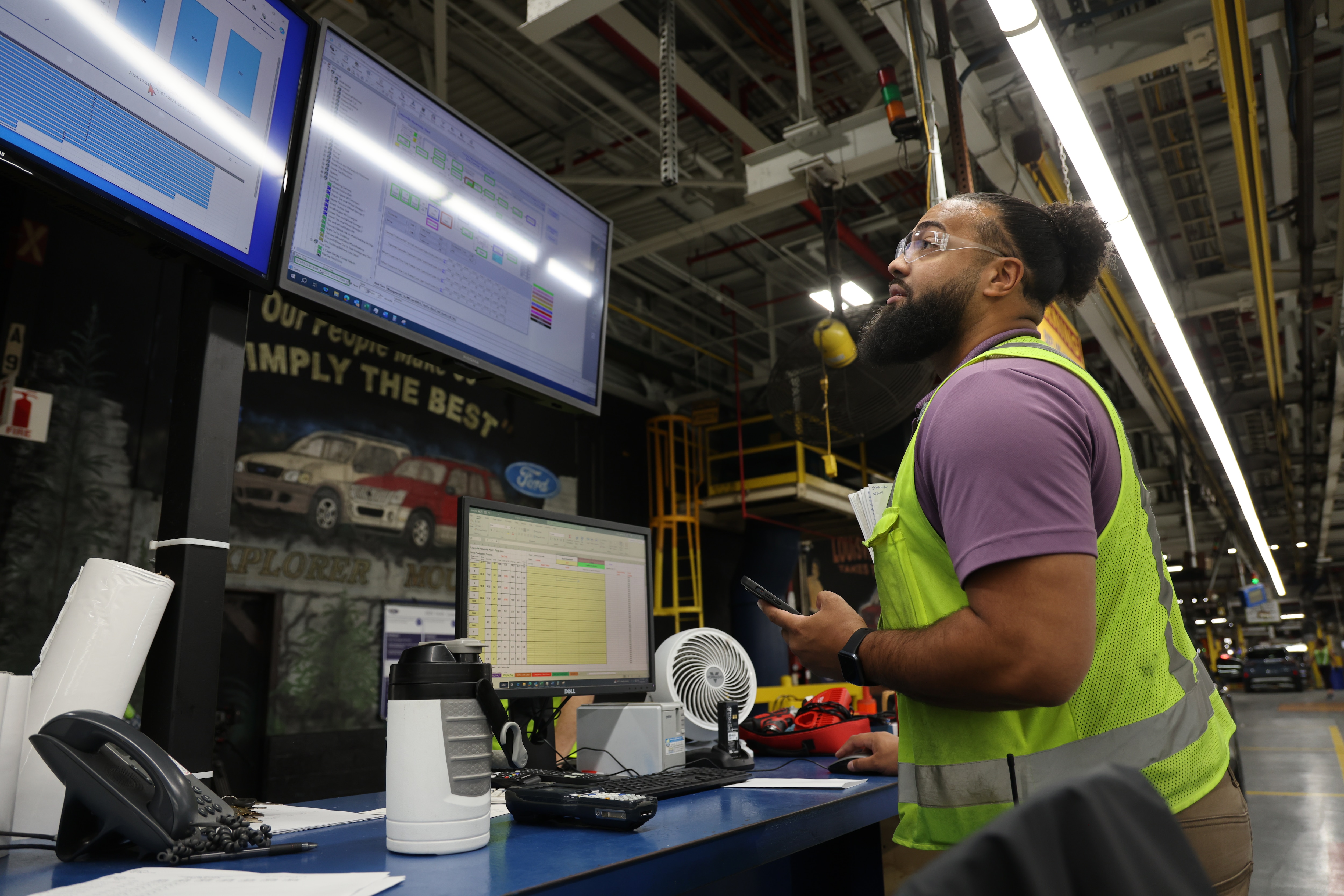 Employee in high visibility vest viewing screens of manufacturing data